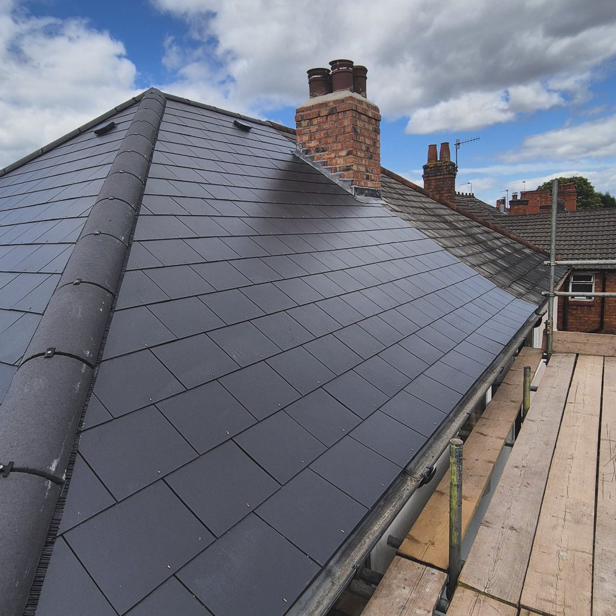 Natural slate re-roof on detached house, blue sky, Birmingham